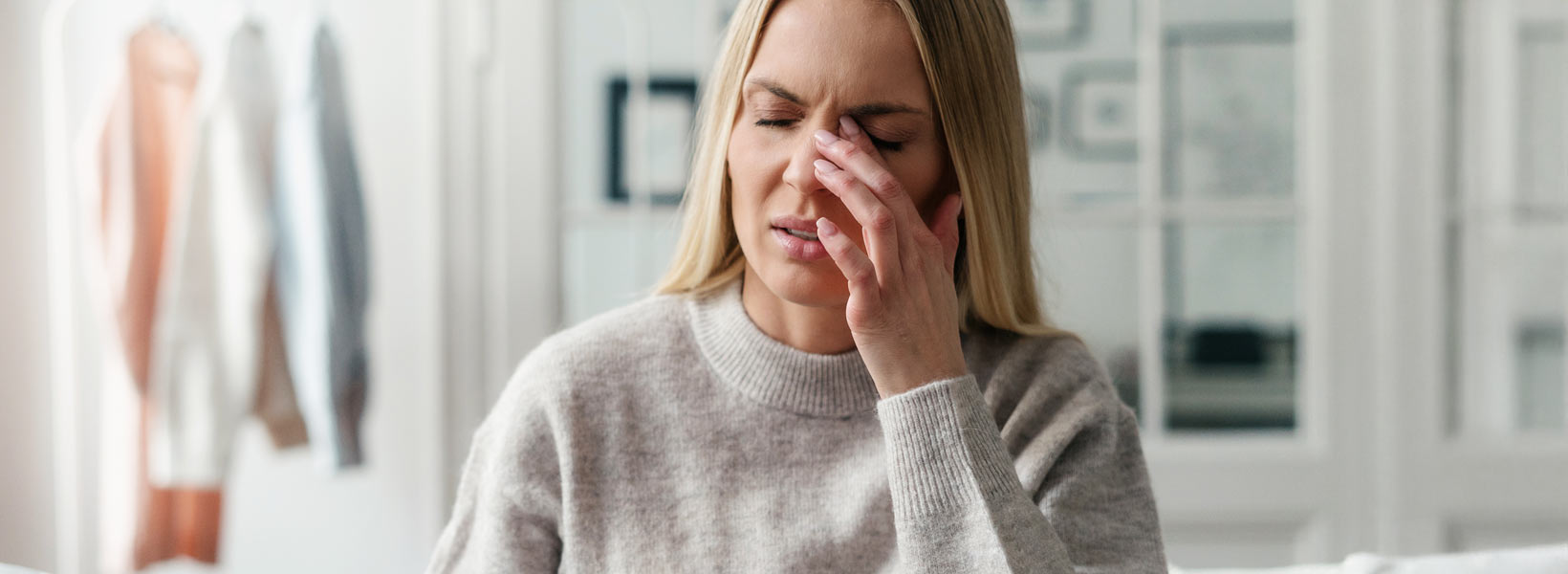 Henkilö rintakehästä ylöspäin. Henkilö hieroo toisella kädellä silmäänsä.