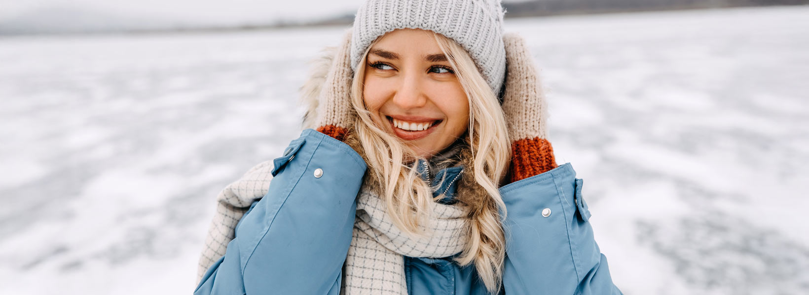 Keskellä kuvaa nainen talvivaatteissa. Taustalla näkyy talvimaisema.